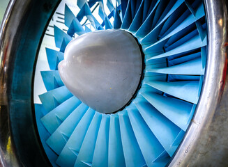 Close-up view of a jet engine turbine showcasing blue blades and a smooth metal casing in an...