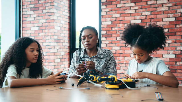 STEM Education Teacher Teaching Diverse School Kid to Build and Code a Robot Arm in Classroom With Hands-On Programming, Engineering, and Technology Learning