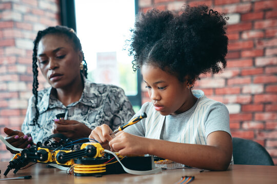 STEM Education Teacher Teaching Diverse School Kid to Build and Code a Robot Arm in Classroom With Hands-On Programming, Engineering, and Technology Learning
