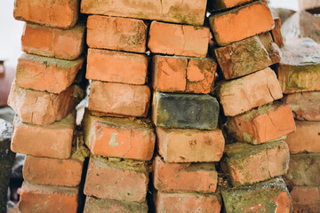 Photo of red bricks stacked evenly but with a slight tilt and minor irregularities. The bricks feature natural texture, adding authenticity and realism to the image. Perfect for construction, architec