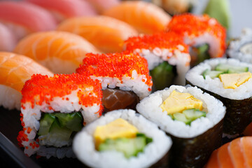 Close-up of assorted sushi rolls and nigiri, featuring salmon, cucumber, tamago, and tobiko; vibrant, fresh food photography.
