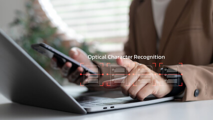 Close-up of a businesswoman using a smartphone and laptop with an OCR interface scanning documents. Concept of optical character recognition, AI document automation, and smart data extraction.