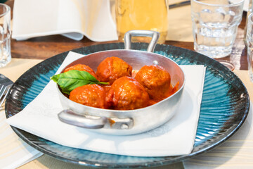 Traditional meatballs served with a basil leaf and tomato sauce.