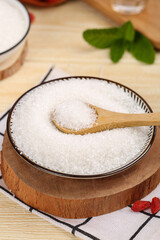 White sugar in a shallow bowl with a wooden spoon for easy serving and measuring