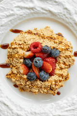 Crumble dessert with berries on white ceramic plate