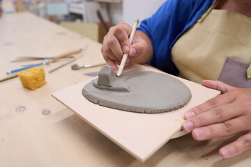 Ceramist using wooden tool modeling clay in workshop