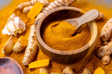 Fresh and Ground Turmeric Root on Rustic Background