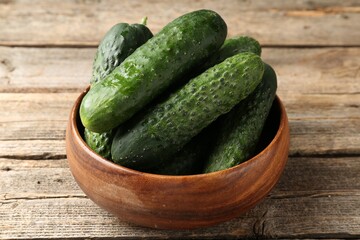 Fresh cucumbers in bowl on wooden table, closeup