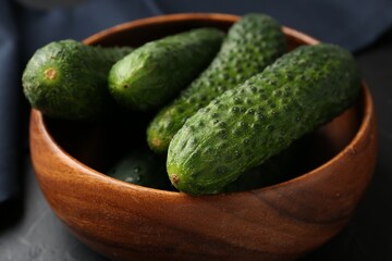Fresh cucumbers in bowl on dark table, closeup