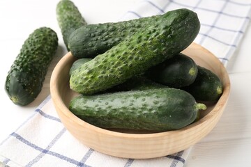 Fresh cucumbers in bowl on white wooden table, closeup