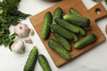 Making pickles. Fresh cucumbers, garlic and herbs on white table, flat lay