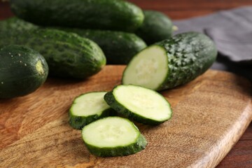 Whole and cut cucumbers on wooden table, closeup