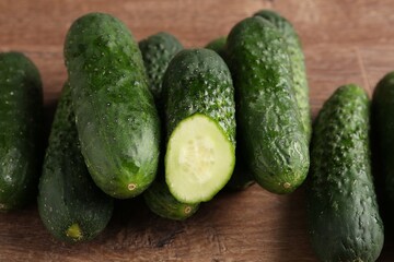 Whole and cut cucumbers on wooden table, closeup