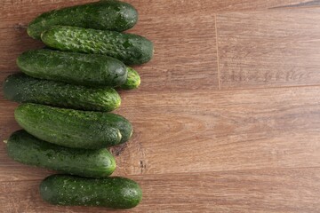 Fresh cucumbers on wooden table, flat lay. Space for text