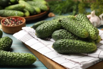 Making pickles. Fresh cucumbers and other ingredients on light blue wooden table, closeup