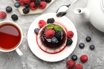 Tasty panna cotta with berries and jam on light grey table, flat lay