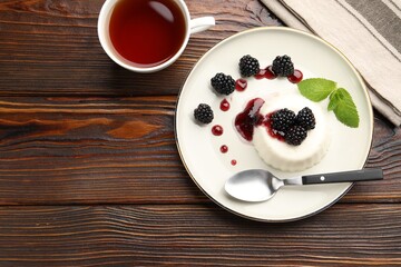 Tasty panna cotta with blackberries, mint and sauce on wooden table, flat lay. Space for text
