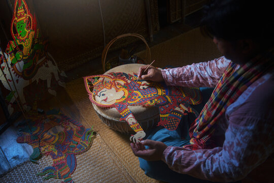 Close-up of a craftsman sitting on the floor making a shadow puppet (Nang Talung)