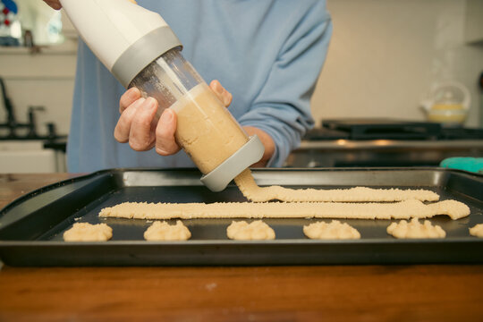 Close-up of a senior woman using a cookie press to make star shaped butter cookies on a baking tray