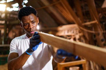 Professional African male carpenter is working professionally in sawmill - workshop.