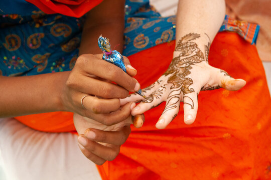 Close-up of a woman's hands being decorated with henna as part of a pre-wedding ritual, India