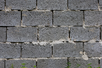 The texture of a wall made of gray concrete blocks. The rough surface of the blocks and the cement joints create an industrial and solid background.