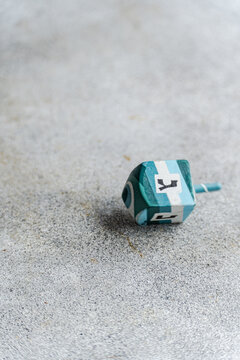 Close-up of a blue and white Wooden hanukkah dreidel on a ceramic table