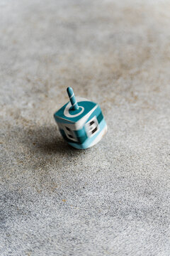 Close-up of a blue and white Wooden hanukkah dreidel on a ceramic table