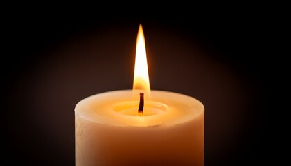 close up of a burning candle with a bright flame against a dark background shot