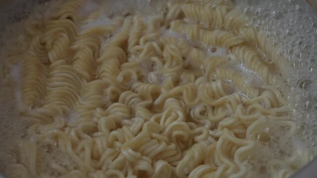 Cooking instant curly noodles in boiling water. Perfect for food blogs, cooking tutorials, and restaurant menus.