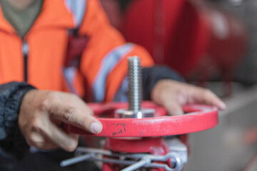 Hand of technical  hold   handle of valve. engineer checking and inspection pressure ,pipeline in fire pump room. High Pressure Water Pump Diesel engine.