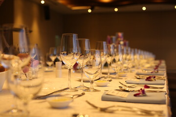 Elegant indoor banquet setup with warm lighting, neatly arranged glassware, folded napkins, and floral accents — perfect for a formal event or celebration.