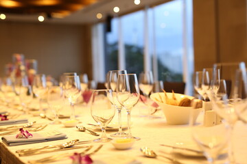 Elegant indoor banquet setup with warm lighting, neatly arranged glassware, folded napkins, and floral accents — perfect for a formal event or celebration.