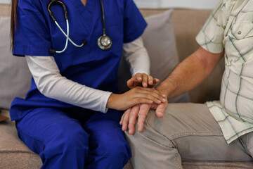 Fototapeta premium A female nurse hold her senior patient's hand. Giving Support. Doctor helping old patient with Alzheimer's disease. Female carer holding hands of senior man 