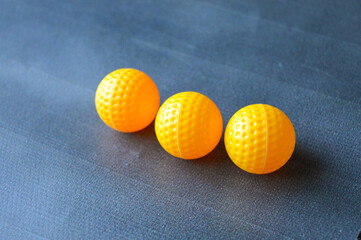 three yellow textured plastic balls arranged in a row on a blue surface. concept of color contrast, children's toys, minimalism, or geometric composition.