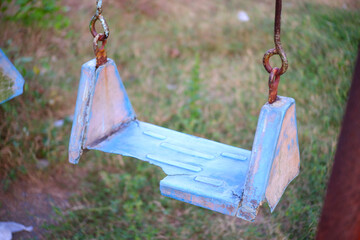 Broken plastic children's swing on the playground, old and unsafe swing. Old blue swing in an...