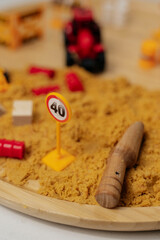 Construction play area features a wooden tool, traffic sign, and colorful building materials in a sandbox setting for creative outdoor learning