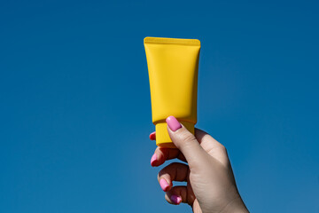 Cosmetic package in hand against blue sky background