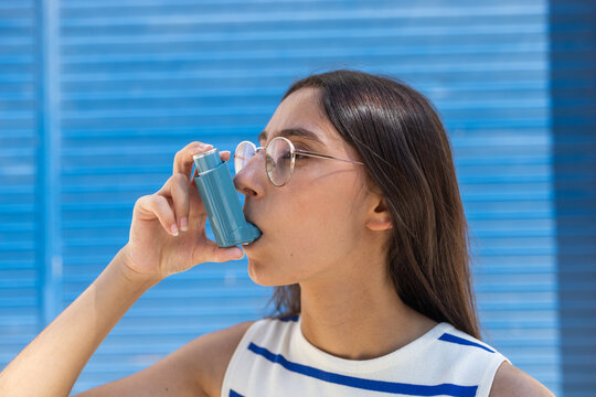 Woman using inhaler against blue background