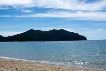 Serene Beach with Distant Hill Under Blue Sky