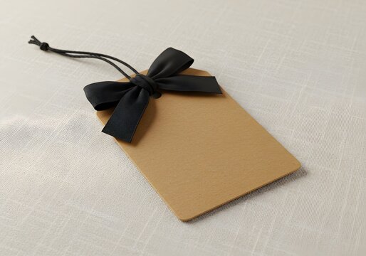 Elegant kraft paper gift tags with black ribbon bows on white background, perfect for luxury packaging and special occasions