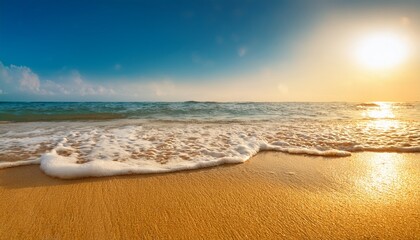 a gentle foamy wave washes over the sparkling golden sand on a sunlit beach creating beautiful bokeh highlights from the ocean water