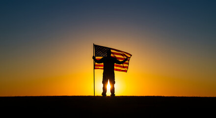 Silhouette of a person holding an American flag against a vibrant sunset, symbolizing patriotism and national pride.