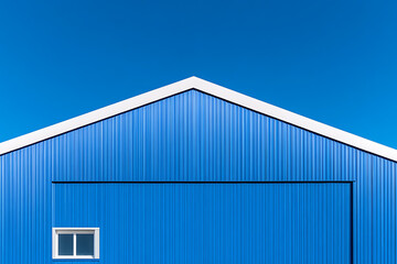 Fototapeta premium Minimalist architecture featuring a blue corrugated metal structure against a clear blue sky, emphasizing geometric shapes and clean lines.