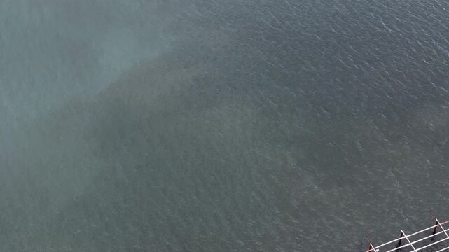 Aerial drone shot of shellfish aquaculture system with metal racks used for oyster farming in ocean water.