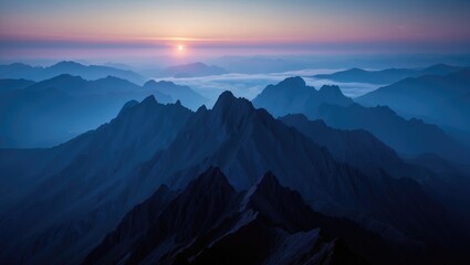 Sunrise over mountain range with layers of peaks and misty atmosphere.
