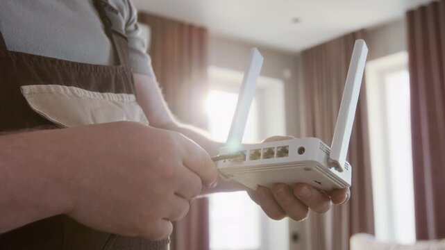 Close up of Caucasian male worker installing internet router with focus on hands plugging in cable with lens flare effect, copy space
