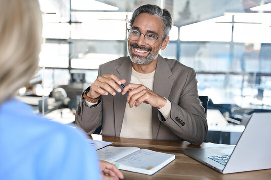 Mature happy professional business man executive, male hr or bank manager or financial advisor having job interview or business conversation consulting talking at corporate office onboarding meeting.