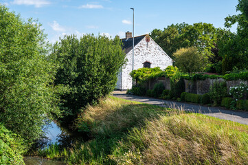 Obraz premium Old house at the Lovaart surrounded with wild green trees in Lo Reninge, West Flanders, Belgium