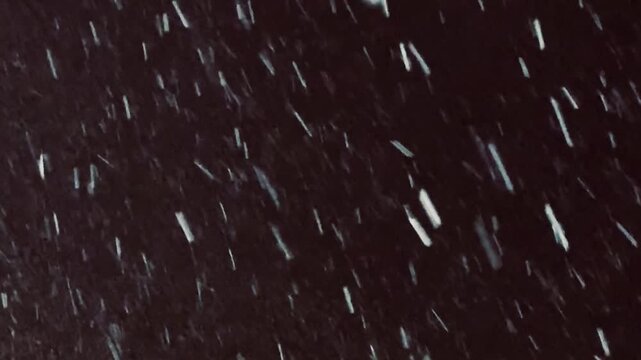 Snow falling with wind in the dark, black sky, macro, close-up video